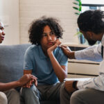 African American woman with a teen son has a meeting with a psychologist.