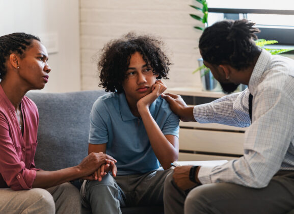 African American woman with a teen son has a meeting with a psychologist.
