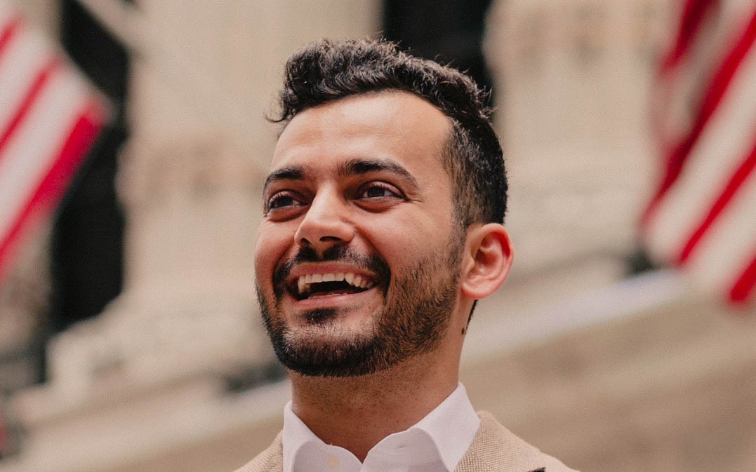 Portrait of Taif Jany. He has short, dark hair, a short beard and a wide smile.