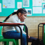 A young Black student looking dejected in a classroom.